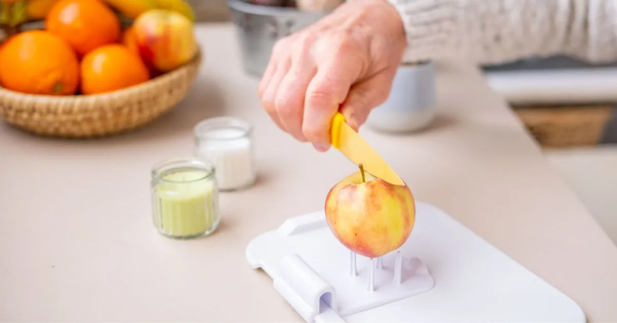 man using adaptive kitchen tool to cut an apple