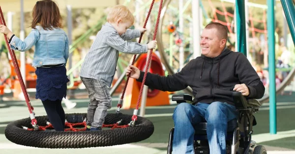 man playing with his son and daughter after a spinal cord injury